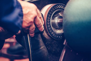 Ayakkabı tamircisi ayakkabının tabanını makinede bitiriyor..