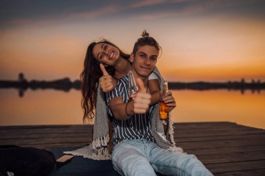 Genç çift eğleniyor ve başparmaklarını kaldırıyor. 