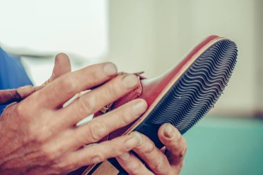 Erkek eli ayakkabıyı tutuyor ve el işi aletleriyle çalışıyor..