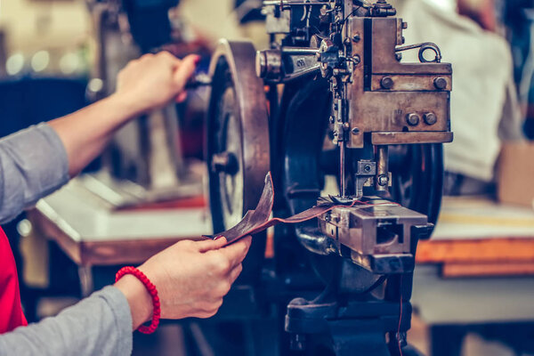 Close up of a female shoemaker hands stitching a part of the sho