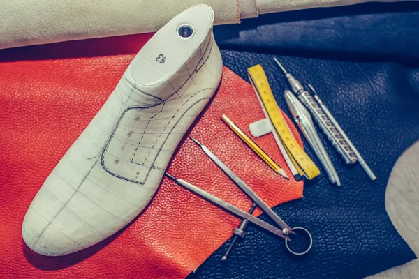 Lugar de trabajo del zapatero con herramientas, cuero y zapatos . — Foto de Stock