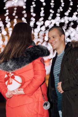 Ayakta duran ve elinde beyaz sürpriz hediye kutusu tutan bir kadın.