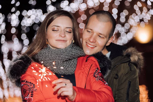 Jeune couple heureux avec des étincelles dans la nuit de la ville d'hiver — Photo