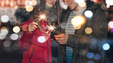 Genç, gülümseyen bir çift kış şehrinde maytaplarla eğleniyor.