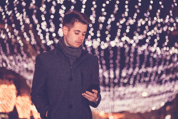 Man with mobile phone on the street with Christmas decoration