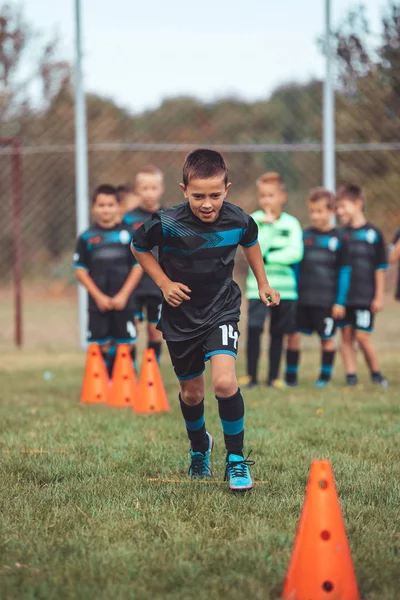 Le jeune footballeur court entre les cônes et le marqueur de l'échelle annulaire — Photo