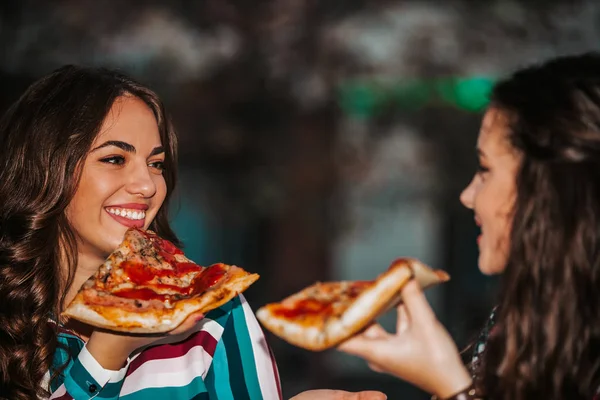 Retrato de dos mujeres jóvenes comiendo pizza al aire libre, divirtiéndose — Foto de Stock