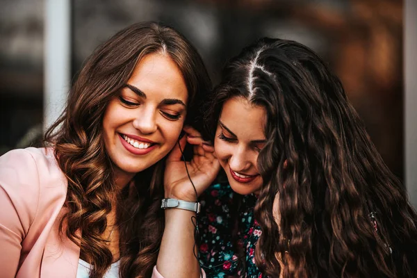 Dos amigos felices compartiendo un teléfono para escuchar música en línea —  Fotos de Stock