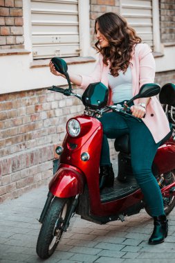 Mutlu neşeli kız scooter 'da oturuyor ve aynaya bakıyor.. 