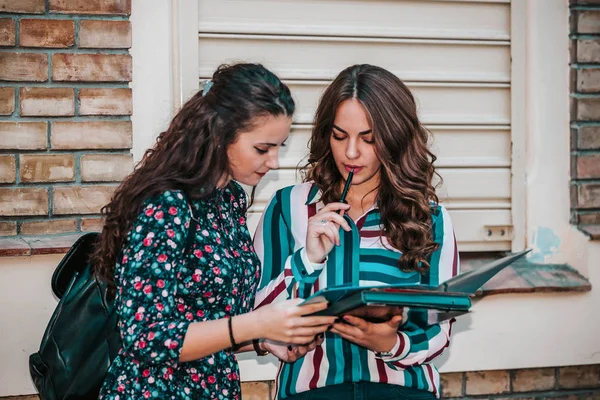 Dos estudiantes felices leyendo un cuaderno y comentando en el stre — Foto de Stock