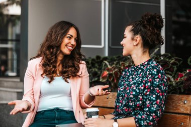 Happy female friends laughing and talking while looking each oth