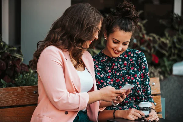 Two happy women friends sharing social media in a smart phone ou