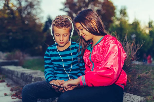 Χαρούμενοι μικροί φίλοι, αγόρι και κορίτσι με ακουστικά που μοιράζονται μουσική — Φωτογραφία Αρχείου