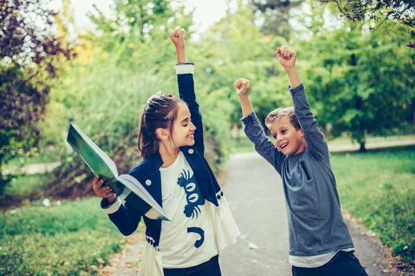 Due bambini felici che festeggiano risultati eccellenti in un test a scuola — Foto Stock