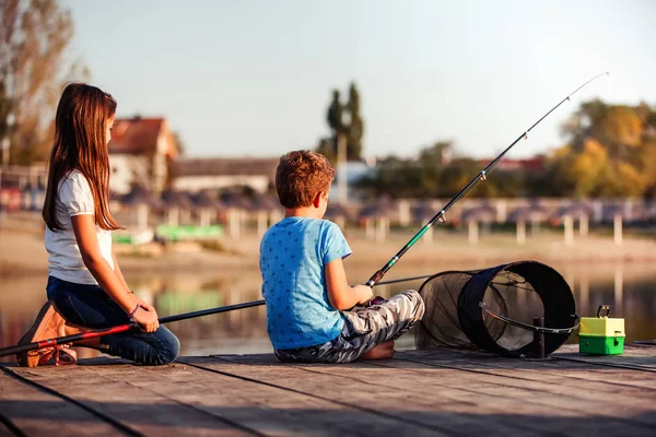 两个年轻可爱的小朋友 男孩和女孩在阳光明媚的夏日里在湖上钓鱼 孩子们在玩友谊 — 图库照片