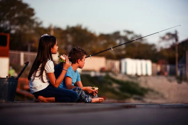 两个年轻可爱的小朋友 男孩和女孩在阳光明媚的夏日里在湖上钓鱼 孩子们在玩友谊 — 图库照片