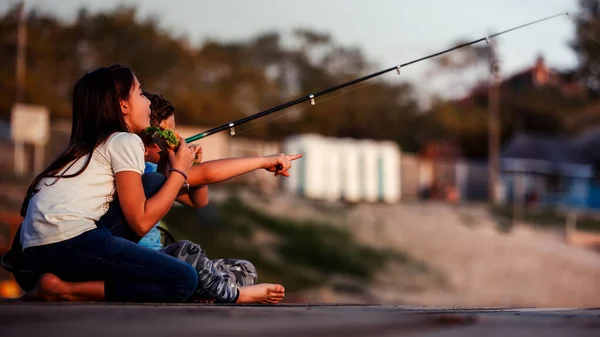 两个年轻可爱的小朋友 男孩和女孩聊天 吃三明治 在阳光明媚的夏日在湖面上钓鱼 孩子们在湖上玩耍 指指点点 — 图库照片