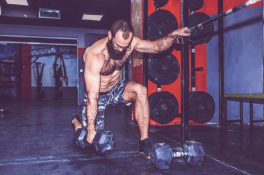 Spor salonunda ağırlık kaldırma yapan genç sakallı adam