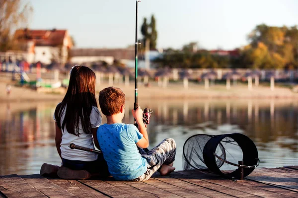 Two young cute little friends, boy and girl fishing on a lake in a sunny summer day. Kids are playing. Friendship.