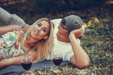 Güzel bir çift parkta çimde dinlenirken konuşuyor ve sarılıyor. 