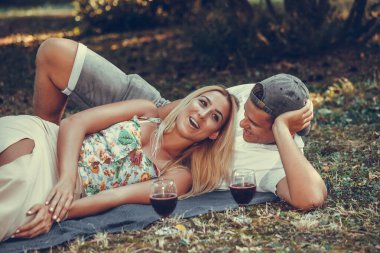 Güzel bir çift parkta çimde dinlenirken konuşuyor ve gülüyor. 