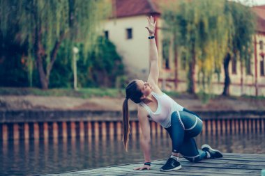 Güzel sporcu kadın nehir kenarında, açık havada egzersiz yapıyor..