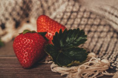 Kırsal kahverengi ahşap arka planda yaprakları olan taze çilekler.