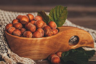 Yeşil yapraklı fındıklar ahşap kasede, kırsal kahverengi arka planda.. 