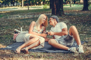 Güzel bir çift parktaki çimlerin üzerinde eğlenirken konuşuyor ve flört ediyor.