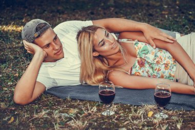 Güzel bir çift parkta çimde dinlenirken konuşuyor ve sarılıyor. 