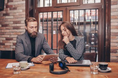 İki iş arkadaşından oluşan bir ekip, kafede otururken tablet kullanarak yeni projeyi tartışıyor..