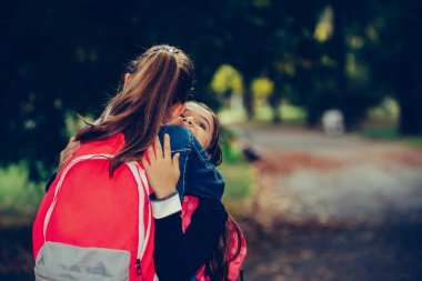 Two school friends hugging, meet in the park. Walking into each other with open arms and smiling. The concept of school, study, education, friendship, childhood