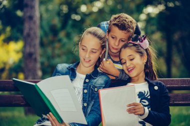 Okula dönelim. Sırt çantalı çocuklar eğleniyor, konuşuyor, kitap okuyor. Bir grup ilkokul öğrencisi bankta otururken ödevlerini tartışıyorlar..