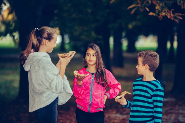 Three Happy Children Talking Eating Pizza Outdoors Having Fun Together — Stok fotoğraf