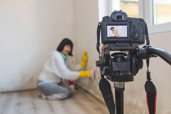 Video camera filming how woman cleaning mold from wall in her house using spray bottle with mold removal products .