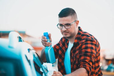 Delikanlı arabasını mikrofiber bezle dikkatlice temizleyip şişeye sıktı..