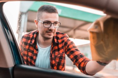 Dışarıdan arabasının camlarını temizleyen genç bir adamın fotoğrafı..