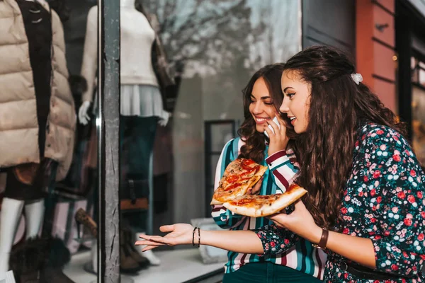 Портрет Двух Красивых Молодых Женщин Говорящих Поедающих Пиццу Улице Указывающих — стоковое фото