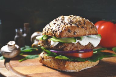 Vejetaryen burger, karabuğday, domates, soğan, vejetaryen mayonez ve keten tohumu ve susamlı taze ekmeğin üzerinde ıspanak, ıspanak yaprakları, mantarlar, domates, karabiber ve baharatla çevrili..