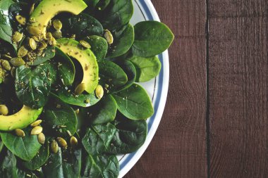 Avokado, ıspanak ve balkabağı tohumlu zeytinyağı ve limon suyuyla tatlandırılmış faydalı bir salata. Sağlıklı yemek..