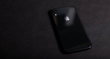 Siyah arka planda siyah bir iPhone. Apple 'ın logosu Apple iPhone Xr' de. Kiev, Ukrayna 03.03.2020