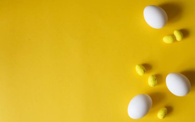 Paskalya teması düzdü. Sarı arka planda beyaz ve sarı Paskalya yumurtaları. Düzenleme dekorasyonunun en iyi görüntüsü. Mutlu Paskalya tatili arka plan kavramı. Metin için boşluk, düzenle