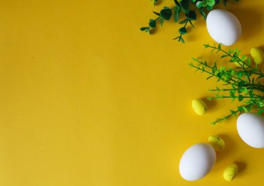 Paskalya teması düzdü. Sarı arka planda beyaz ve sarı Paskalya yumurtaları. Düzenleme dekorasyonunun en iyi görüntüsü. Mutlu Paskalya tatili arka plan kavramı. Metin için boşluk, düzenle