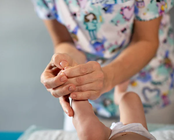 Mulher mãos massagem bebê perna — Fotografia de Stock