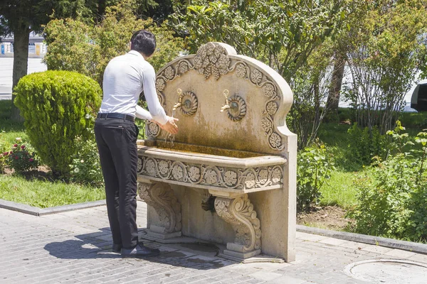 A man washes his hands under a tap with free water installed in a city Park. Tap with free water in the city Park for washing and quenching your thirst.