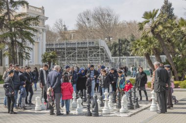 Bakü, Azerbaycan-25 Mart 2018, sahil parkındaki büyük satranç sahası. Satranç oynamaya tutkulu insanlar. Azerbaycan Cumhuriyeti 'nde sporun kitlesel gelişimi. Spor, hobiler, insanlar