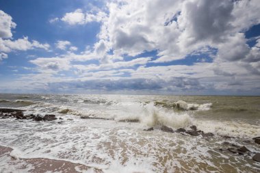 Deniz dalgası sörfü. Bol köpüklü deniz dalgaları. Ön planda, çakıl taşı plajında. Su elementi, heyecan, kötü hava. 