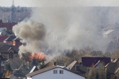 Yanan evlerin arasında bir yerleşim köyünde sigara içmek. Yangının arka planına karşı evler yıkım ve felaket getiriyor..