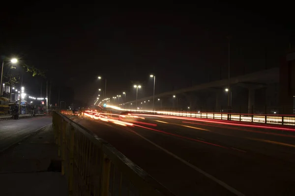 Hastighet Trafik ljus spår på motorvägen, lång exponering, urban bakgrund och mörk himmel — Stockfoto