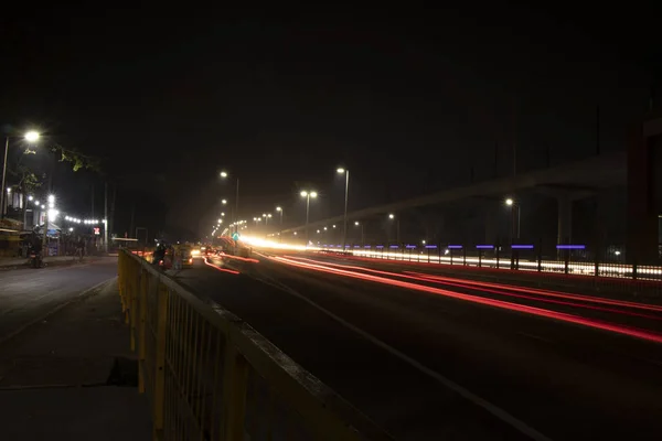 Velocidade Trilhas de semáforo na estrada, exposição longa, fundo urbano e céu escuro — Fotografia de Stock